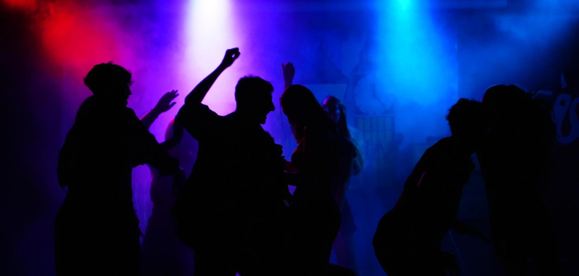 Persone che ballano in una discoteca con luci colorate e atmosfera festosa.